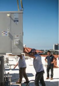 man guiding large ac unit as it's moved